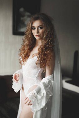 Cüppeli muhteşem gelin bir odada düğün töreni için poz veriyor ve hazırlanıyor.