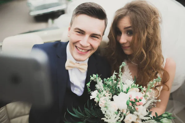 Szczęśliwa Panna młoda i pan młody Dokonywanie selfie na ich ślubie w retro samochodów — Zdjęcie stockowe