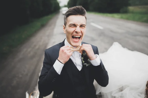 Красивий наречений на весіллі посміхається і чекає нареченої біля ретро-автомобіля — стокове фото