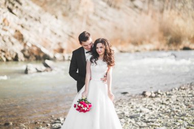 Düğün çifti, damat ve gelin kucaklaşıyor, nehir kenarında.