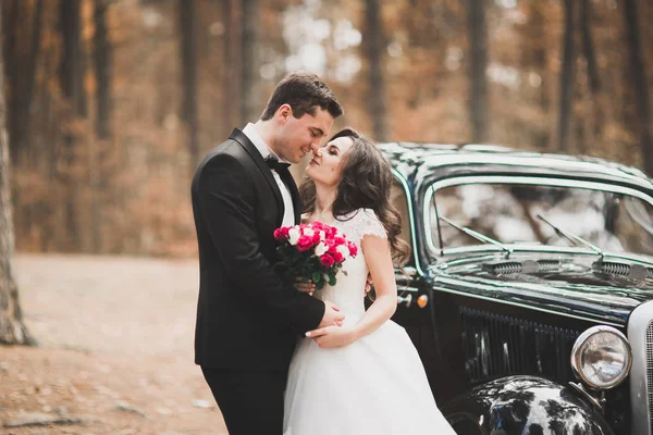 Stylish wedding couple, bride, groom kissing and hugging on retro car — Stock Photo, Image