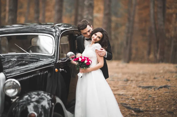 Beautiful wedding couple posing near splendid retro car — Stock Photo, Image