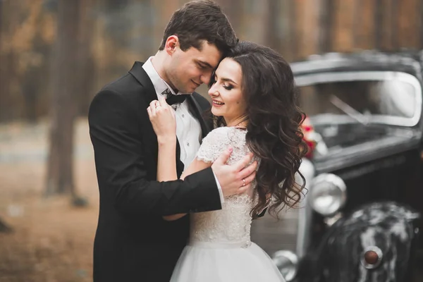 Stylish wedding couple, bride, groom kissing and hugging on retro car — Stock Photo, Image