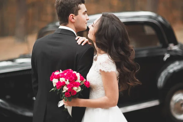 Elegante coppia di nozze, sposa, sposo baciare e abbracciare vicino auto retrò in autunno — Foto Stock