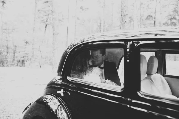 Hermosa pareja de boda posando cerca de espléndido coche retro — Foto de Stock