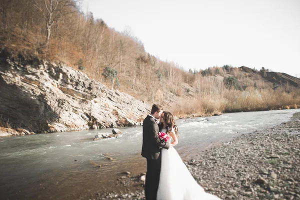 Bruidspaar, bruidegom en bruid knuffelen, buiten bij rivier — Stockfoto