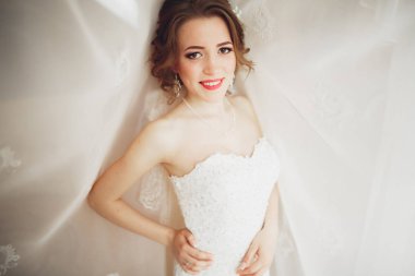 Beyaz elbiseli lüks gelin düğün törenine hazırlanırken poz veriyor.