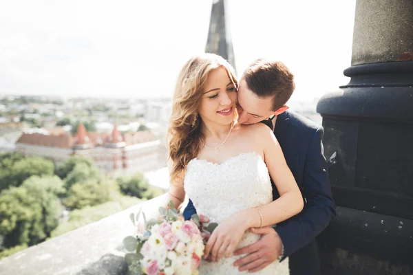 Стильна красива весільна пара цілується і обіймається на фоні панорамного вигляду старого міста — стокове фото