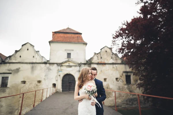 Feliz casamento casal abraçando e sorrindo uns aos outros no fundo velho castelo — Fotografia de Stock