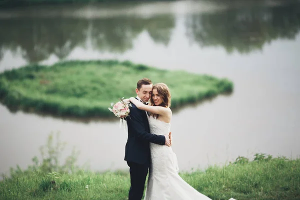 Casal de casamento lindo beijando e abraçando perto do lago com a ilha — Fotografia de Stock