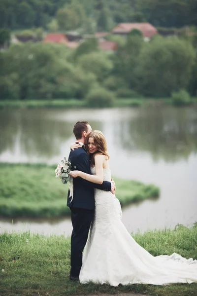 Casal de casamento lindo beijando e abraçando perto do lago com a ilha — Fotografia de Stock