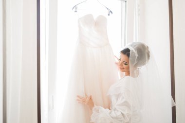 Cüppeli muhteşem gelin bir odada düğün töreni için poz veriyor ve hazırlanıyor.