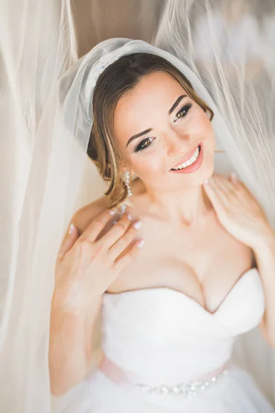 Preciosa novia en bata posando y preparándose para la ceremonia de boda cara en una habitación —  Fotos de Stock