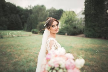 Parkta poz veren zarif beyaz elbiseli güzel gelin.