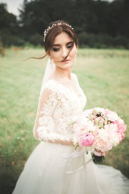 Parkta poz veren zarif beyaz elbiseli güzel gelin.