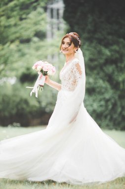 Çekici gelinin portresi, uzun saçlı, büyük buketli poz veren.