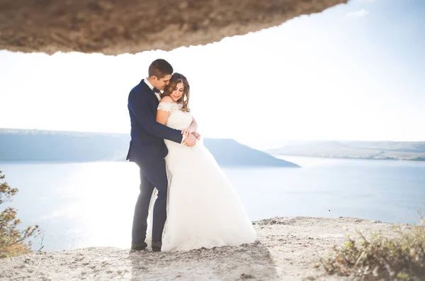 Hochzeitspaar küsst und umarmt sich auf Felsen nahe blauem Meer — Stockfoto