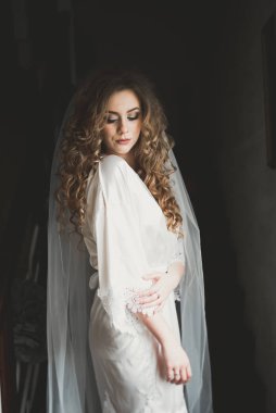 Cüppeli muhteşem gelin bir odada düğün töreni için poz veriyor ve hazırlanıyor.