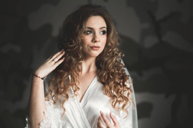 Cüppeli muhteşem gelin bir odada düğün töreni için poz veriyor ve hazırlanıyor.