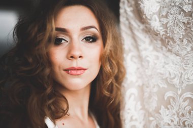 Cüppeli muhteşem gelin bir odada düğün töreni için poz veriyor ve hazırlanıyor.