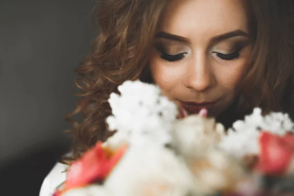 Preciosa novia en bata posando y preparándose para la ceremonia de boda cara en una habitación —  Fotos de Stock