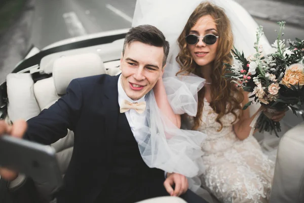 Felice sposa e sposo fare selfie al loro matrimonio in auto retrò — Foto Stock