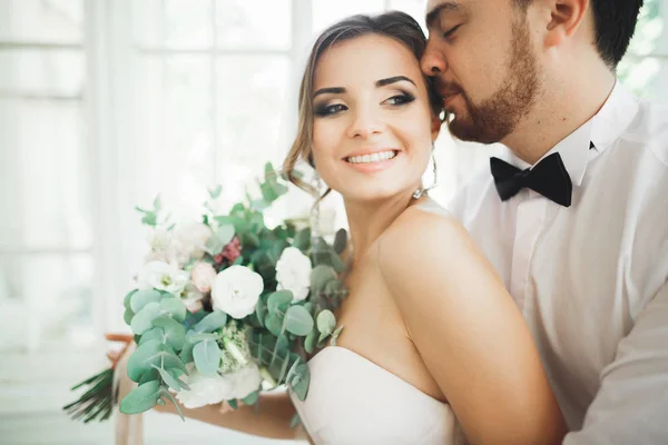 Espléndido novio abrazando suavemente novia elegante. Momento sensual de pareja de boda de lujo — Foto de Stock