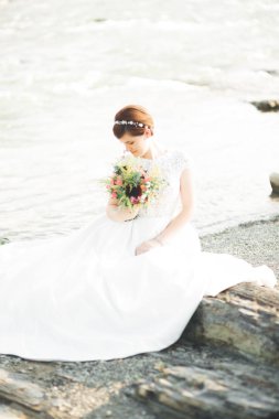 Buket ile nehrin yanında poz ise muhteşem güzel gelin gülümsüyor