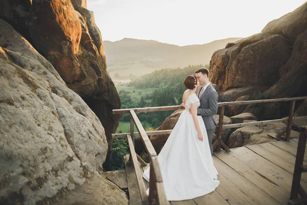 年轻夫妇，新婚夫妇，新郎新娘亲吻，拥抱在完美的山景，蔚蓝的天空 — 图库照片