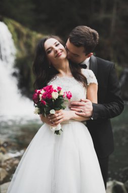 Düğün çifti, damat ve gelin kucaklaşıyor, nehir kenarında.