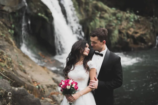 Elegantní stylový šťastný Černovlásky nádherný ženicha a na pozadí krásné řeky v horách — Stock fotografie