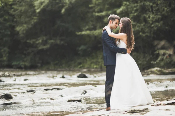 Elegantní jemný stylový ženich a nevěsta v blízkosti řeky s kameny. Svatební pár v lásce — Stock fotografie