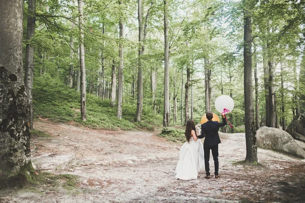 Young funny happy wedding couple outdoors with ballons