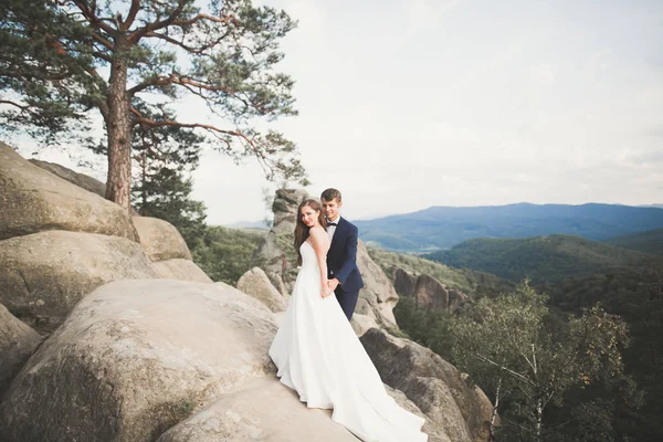 Linda noiva, noivo beijando e abraçando perto das falésias com vistas deslumbrantes — Fotografia de Stock