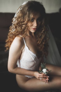 Cüppeli muhteşem gelin bir odada düğün töreni için poz veriyor ve hazırlanıyor.