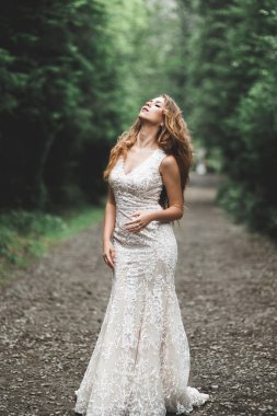 Parkta poz veren zarif beyaz elbiseli güzel gelin.