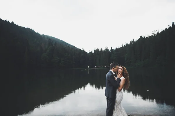 Hermosa pareja de boda besándose y abrazándose cerca de la montaña con vista perfecta — Foto de Stock
