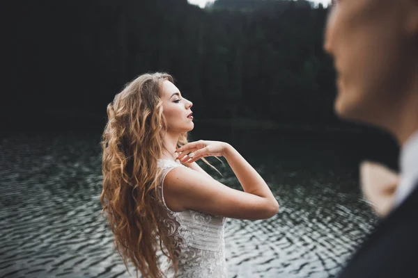 Jovem casal recém-casado, noiva e noivo beijando, abraçando na visão perfeita das montanhas, céu azul — Fotografia de Stock