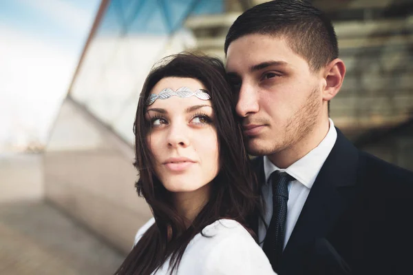 Stijlvolle liefdevolle paar zoenen en knuffelen in de buurt van modern gebouw — Stockfoto