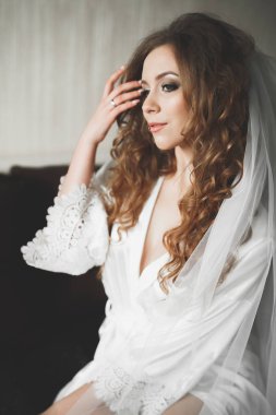 Cüppeli muhteşem gelin bir odada düğün töreni için poz veriyor ve hazırlanıyor.