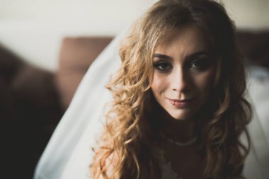 Cüppeli muhteşem gelin bir odada düğün töreni için poz veriyor ve hazırlanıyor.