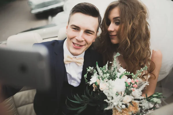 Novia feliz y novio haciendo selfie en su boda en coche retro — Foto de Stock