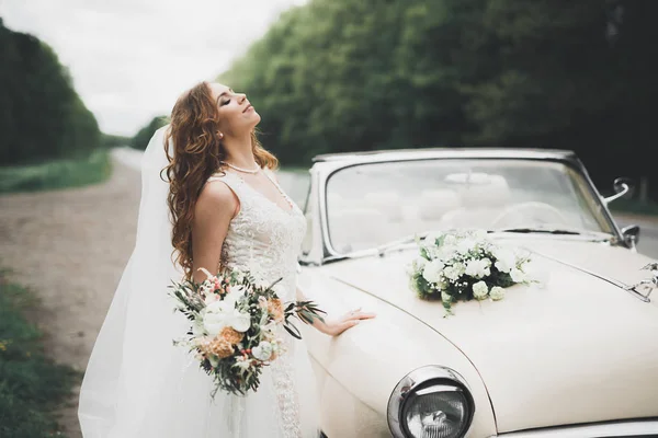 Glückliche Braut im Retro-Auto posiert an ihrem Hochzeitstag — Stockfoto