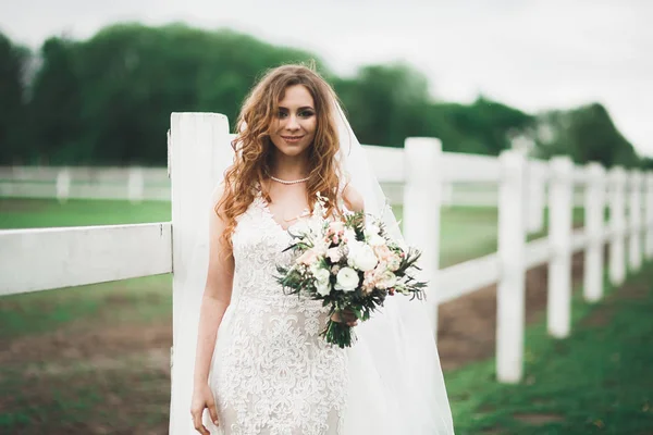 Retrato de novia impresionante con el pelo largo posando con gran ramo — Foto de Stock