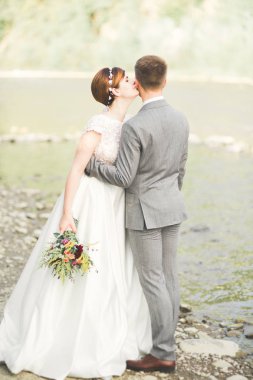 Gelin ve damat güzel düğün buket tutarak. Nehir kenarında poz