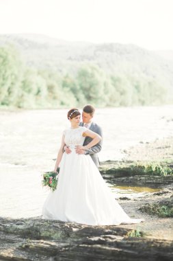 Gelin ve damat güzel düğün buket tutarak. Nehir kenarında poz