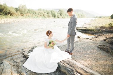 Zarif nazik şık damat ve gelin taşlarla Nehri yakınında. Evlilik çift aşık