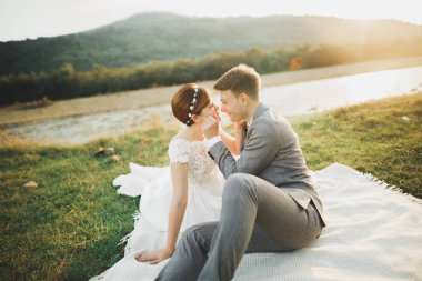 Yeni evli çift, gelin ve damat öpüşüyor, mükemmel dağ manzarasında sarılıyorlar, mavi gökyüzü