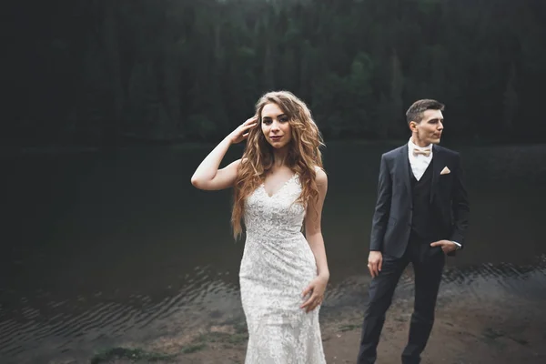 Joven pareja recién casada, novia y novio besándose, abrazándose a la vista perfecta de las montañas, cielo azul — Foto de Stock