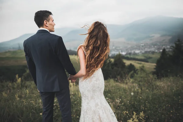 Gyönyörű gyönyörű menyasszony pózol vőlegény és szórakozás, luxus szertartás a hegyekben csodálatos kilátás, hely a szöveg, esküvői pár — Stock Fotó